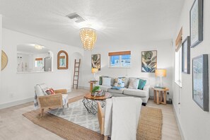 Ein modernes Wohnzimmer mit einer Couch, Sesseln, einem Couchtisch und Kunstwerken an den Wänden.