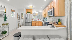 Una cocina moderna con armarios blancos, electrodomésticos de acero inoxidable y una isla central.