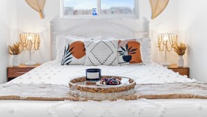 Una cama bien hecha con una bandeja decorativa, almohadas y una mesita de noche con lámpara.