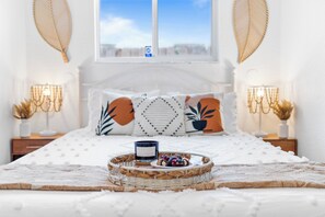 Ein ordentlich gemachtes Bett mit dekorativer Ablage, Kissen und Nachttisch mit Lampe.