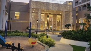 Un patio con un parque infantil, un edificio de fachada decorada y un camino.