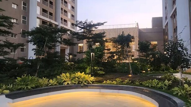 Un patio con una fuente circular, rodeado de vegetación y edificios modernos.