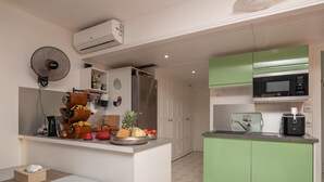 Una cuina compacta amb nevera, microones i una petita illa amb un ventilador i diversos elements de cuina.