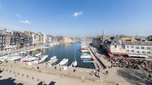 Een jachthaven met aangemeerde boten, een promenade langs het water en gebouwen aan de kust.