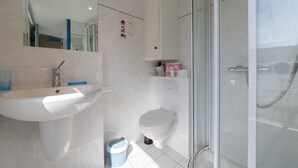 Een moderne badkamer met een wastafel, toilet en douchecabine van glas.
