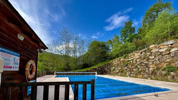 A swimming pool with a wooden deck, a lifebuoy, and a signboard. - La Bulle d’Ax - Domaine de la Vallée d'Ax (Ax-les-Thermes)