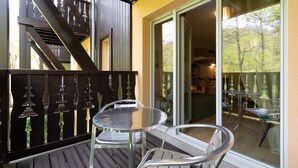 A balcony with a table and chairs, a wooden staircase, and a glass door leading to an outdoor area. - La Bulle d’Ax - Domaine de la Vallée d'Ax (Ax-les-Thermes)