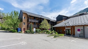 A building with a parking lot, a reception area, and a sign indicating a no parking zone. - La Bulle d’Ax - Domaine de la Vallée d'Ax (Ax-les-Thermes)