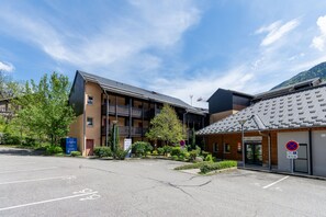 A building with a parking lot, a reception area, and a sign indicating a no parking zone. - La Bulle d’Ax - Domaine de la Vallée d'Ax (Ax-les-Thermes)