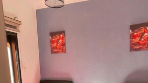 Una habitación con dos camas, una ventana y obras de arte en las paredes.