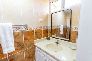 Un baño con lavamanos, espejo y toallero.