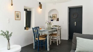 A dining area with a wooden table, blue chairs, and a dark door. - Grand Village Stay for Seven (Santorini)