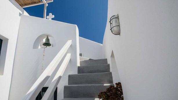 A white building with a bell and a light fixture. - Grand Village Stay for Seven (Santorini)