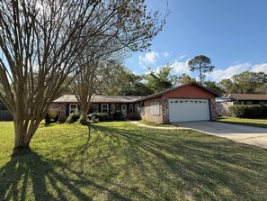 A residential house with a garage, a lawn, and a tree.