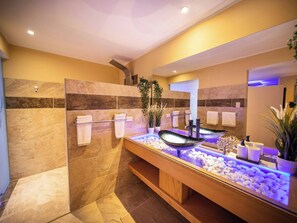 Ein modernes Badezimmer mit einem Waschbecken aus Glas, Marmorfliesen und einem Handtuchhalter.
