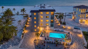 Ein Hotel am Strand mit Pool, mehreren Balkonen und Meerblick.