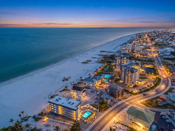 A coastal hotel with multiple buildings, a swimming pool, and a beach view. - Beachfront Escape with Pool, Tiki Huts & Stunning Gulf Views - Casa Bleu - Roelens (Fort Myers Beach)