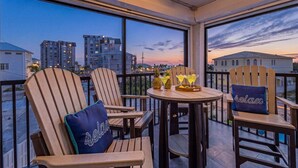 Ein Balkon mit Holzkstühlen, einem Tisch und Blick auf Gebäude im Abendrot.
