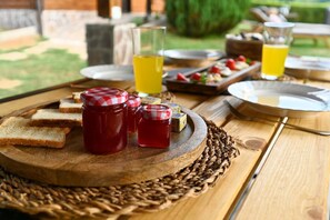 Ein Holztisch mit Gläsern Marmelade, Brotscheiben und einem Glas Saft.