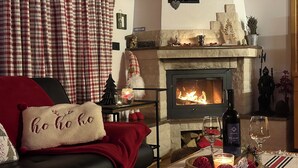 Ett mysigt vardagsrum med en öppen spis, en soffa och festliga dekorationer.