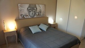 A bedroom with a bed, two bedside lamps, a nightstand, and a wall-mounted artwork.