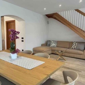 Ein modernes Wohnzimmer mit einem Holzesstisch, einer Couch und einer Treppe.
