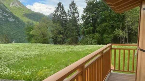 Um deck de madeira com vista para um campo verde e montanhas.