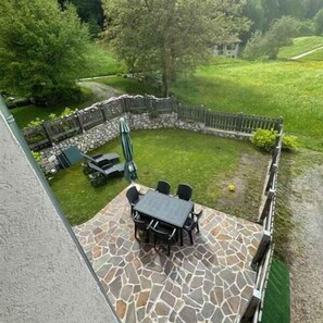 Une terrasse avec un sol en pierre, une table et des chaises.