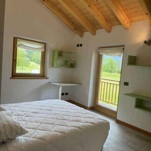 Ein Schlafzimmer mit Bett, Fenster, Balkon und eingebauten Regalen.