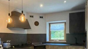 Cozinha moderna com armários de madeira, ilha central, iluminação pendente e uma janela com vista.