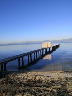 Une jetée s’avançant dans une eau calme, sous un ciel dégagé.