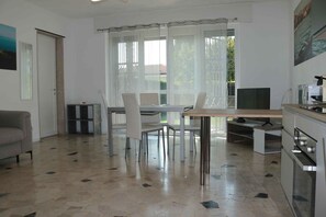 A modern kitchen with a dining area, a sofa, and a TV. - Holiday apartment by the water with shared boat dock (Mattarana)