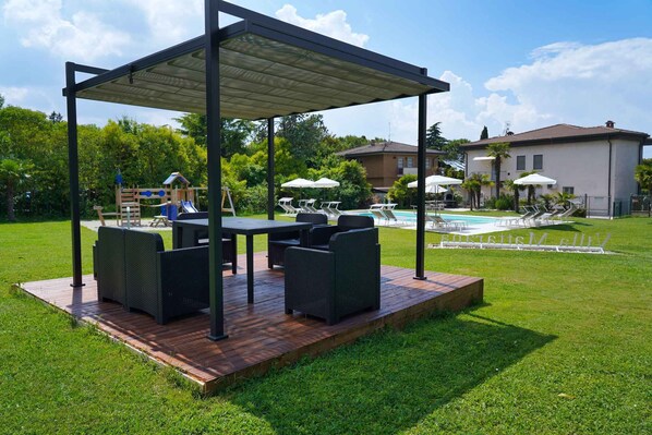 Un espace extérieur aménagé, abrité, avec une piscine et des chaises longues en arrière-plan.