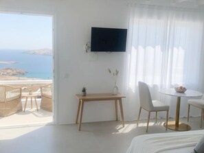 A hotel room with a balcony, a TV, a dining table, and a bed. - Seaview Retreat Facing the Aegean (Mykonos)