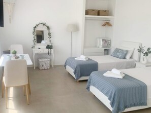 A hotel room with two beds, a desk, a chair, a mirror, and a wardrobe. - Seaview Retreat Facing the Aegean (Mykonos)