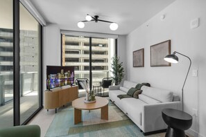 Ein modernes Wohnzimmer mit Fernseher, Sofa, Couchtisch und Stehlampe.