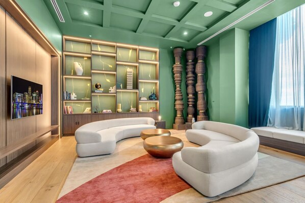 Ein modernes Wohnzimmer mit einer gebogenen Couch, einem Couchtisch und einem an der Wand montierten Fernseher.