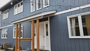 Ein zweistöckiges Haus mit Veranda, einer Holzleiter und einer weißen Tür.