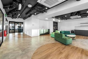 A modern interior with a reception desk, green seating, and a fire extinguisher. - Adelaide Central 1+1 Apt | Gym | Sleeps 4 Guests (Adelaide)