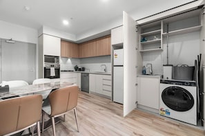 A modern kitchen with a dining area, a washing machine, and a built-in oven. - Adelaide Central 1+1 Apt | Gym | Sleeps 4 Guests (Adelaide)
