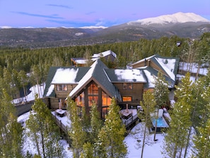 A log cabin with a deck, surrounded by snow-covered trees and a mountain in the background. - The Ski Classic Lodge - Ski in / out at Peak 8 - Pick your Perk! (Breckenridge)