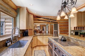 A kitchen with wooden beams, granite countertops, a built-in stove, and a sink. - The Ski Classic Lodge - Hike in / out at Peak 8 in the best location in Breck (Breckenridge)