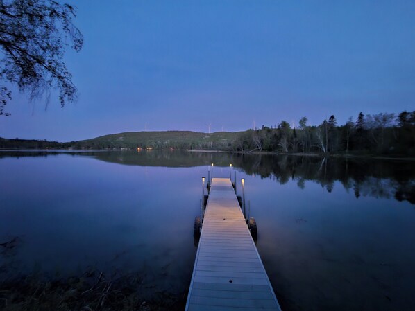 A wooden dock extending into calm water with a clear view of the surrounding landscape. - Spaulding Lake Cottage: 4-acre lakefront retreat in Northern Maine (Oakfield)