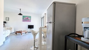 Ett modernt kök med kylskåp, kaffemaskin och en matplats med bord och stolar.