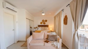 Ein Schlafzimmer mit einem Bett, einer Schlafcouch, einem Deckenventilator und einem Fenster mit Vorhängen.