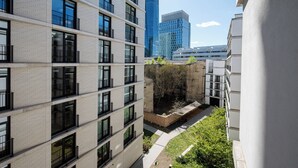 Um edifício de vários andares com varandas, um pátio com vegetação e arquitetura moderna.