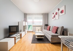 A modern living room with a sofa, TV, and artwork on the wall. - Białołęka Charming Studio (Warszawa)