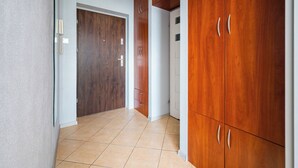 Un pasillo con armarios de madera, una puerta y suelo de baldosas.