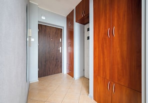 A hallway with wooden cabinets, a door, and tiled flooring.