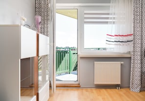 A room with a window, a radiator, and a view of a green fence.